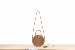 Detail of round straw beach bag with spiral woven texture and circular handle
