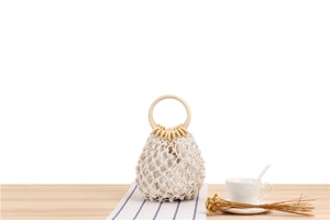 Detail of woven mesh bag with wooden handles and beige inner lining for beach use