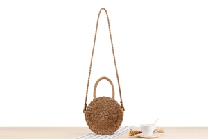 Detail of round handmade woven paper straw bag with top handles and shoulder strap