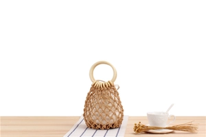 Close-up of handmade woven mesh bag with round wooden handles and cotton inner pouch