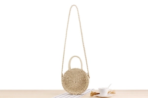 Detail of round straw beach bag showing spiral woven texture and dual handle design