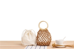 Detail of hand-woven mesh bag with wooden handles and a canvas drawstring inner pouch