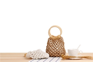 Detail of bohemian handmade woven mesh beach bags with round wooden handles on a table