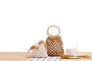Detail of bohemian woven cotton mesh bags with round wooden handles in white and brown colors