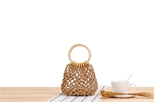 Close-up of handmade woven mesh bag with round wooden handles on a rustic table