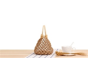 Detail of hand-woven cotton net bag with round wooden handles for summer beach style