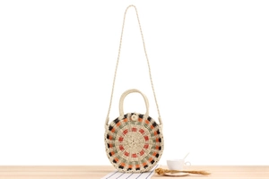 Detailed view of round woven beach bag with colorful patterns on a wooden table