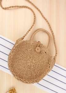 Macro detail of natural straw woven texture and circular handle on a beach tote bag