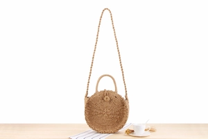 Detail shot of a round hand-woven paper rope bag on a wooden table for summer vacation