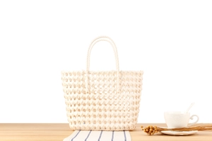 Detail of white woven PVC tote bag showing intricate hollow-out texture and sturdy handles