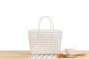Detail of white PVC woven tote bag on a light wood table with a minimalist aesthetic view