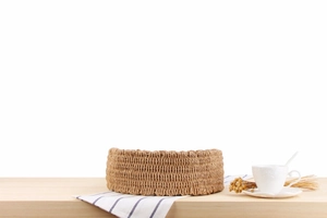 Detail of handcrafted round woven bag with natural straw texture on a wooden table
