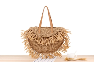 Close-up of woven fringe detail and brown leather handle on summer straw bag