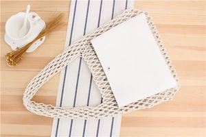 Close-up of beige handmade crochet tote bag with books on a rustic wooden table