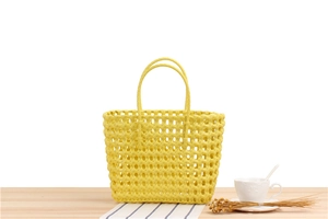 Close-up of bright yellow woven PVC handbag with hollow texture on a white background