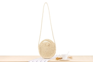 Detailed view of hand-woven round straw bag with spiral texture and button closure