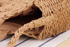 Close-up of handmade woven straw bag featuring reinforced circular handle and fabric lining