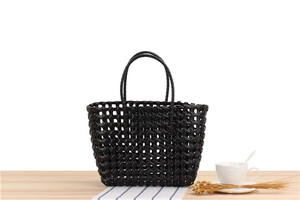 Detail of hand-woven black PVC tote bag with waterproof texture and sturdy handles