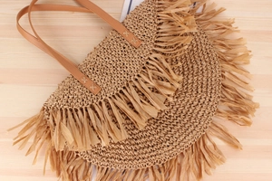 Close-up of bohemian woven straw bag with fringe detailing and brown PU shoulder straps