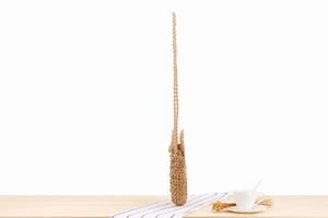 Detailed view of hand-woven straw crossbody bag with natural fiber texture and strap