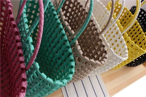 Detailed macro view of multi-color PVC woven handbags showcasing reinforced handles