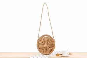 Close-up of a handmade round straw woven crossbody bag with spiral weave texture