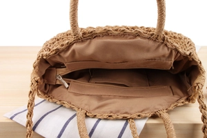 Detailed interior of woven paper straw tote bag with zip pocket and fabric lining