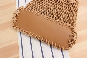 Detail of hand-woven mesh bag with brown faux leather base and bohemian summer style