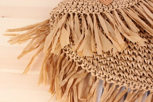 Macro detail of natural straw weaving pattern and long fringes on a bohemian handbag