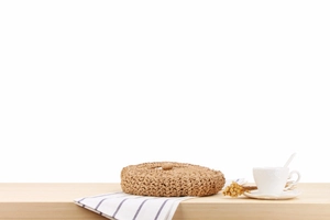 Detailed view of handmade circular straw bag texture on a wooden table for casual beach style