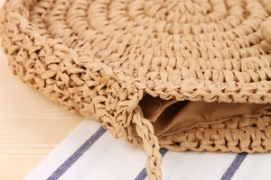 Close-up of handmade round woven straw bag with fabric lining and tight spiral texture