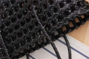 Detail shot of black woven PVC shopping bag texture on a natural wooden tabletop