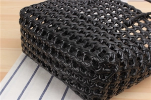 Detailed view of the woven black PVC tote bag featuring a durable cross-weave mesh texture