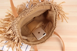 Detail view of woven straw tote bag interior featuring fabric lining and phone pocket