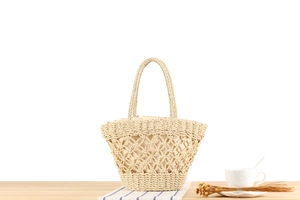 Detail of hollow paper straw woven beach tote bag with soft fabric lining on wooden surface