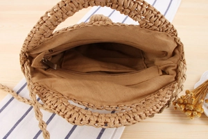 Detail view of woven straw bag interior with brown fabric lining and zip pocket