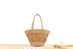 Detail of woven paper straw bag featuring hollow mesh pattern and beige fabric lining