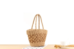 Detail of hand-woven straw handbag with hollow crochet pattern on a wooden surface