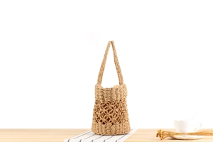 Detail view of straw woven bucket bag featuring hollow mesh and fabric lining