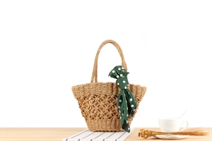 Detail of hand-woven paper rope bag with mesh hollow pattern and green polka dot scarf