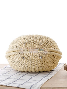 Handwoven shell-shaped straw handbag made of natural fibers with metal studs on base
