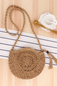 Detail of round straw crossbody bag featuring intricate hand-woven hollow patterns