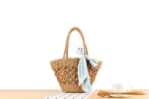 Detail of hand-woven paper rope bag with diamond hollow pattern and blue silk scarf decor