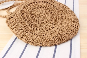 Detailed view of handmade circular straw bag with intricate openwork weave and bow
