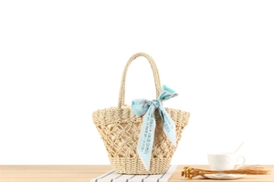 Detail of hand-woven straw bag with hollow diamond pattern and floral blue scarf