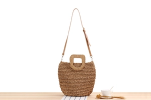 Detail of paper rope woven crossbody bag with wooden handle and adjustable strap