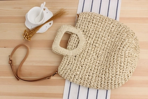 Detail of beige paper rope woven bag with hollow square handle and brown leather strap
