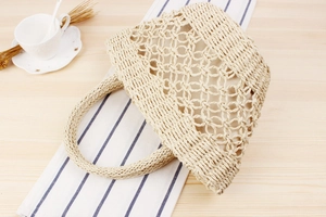 Detail of hand-woven straw tote bag with intricate hollow patterns and sturdy handles