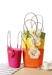 Colorful woven straw bags with floral details on a table in a bright summer setting