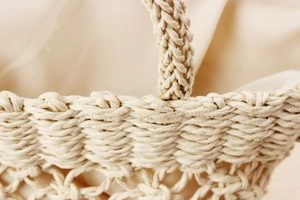 Detailed close-up of natural beige paper rope weaving texture and fabric lining of handbag